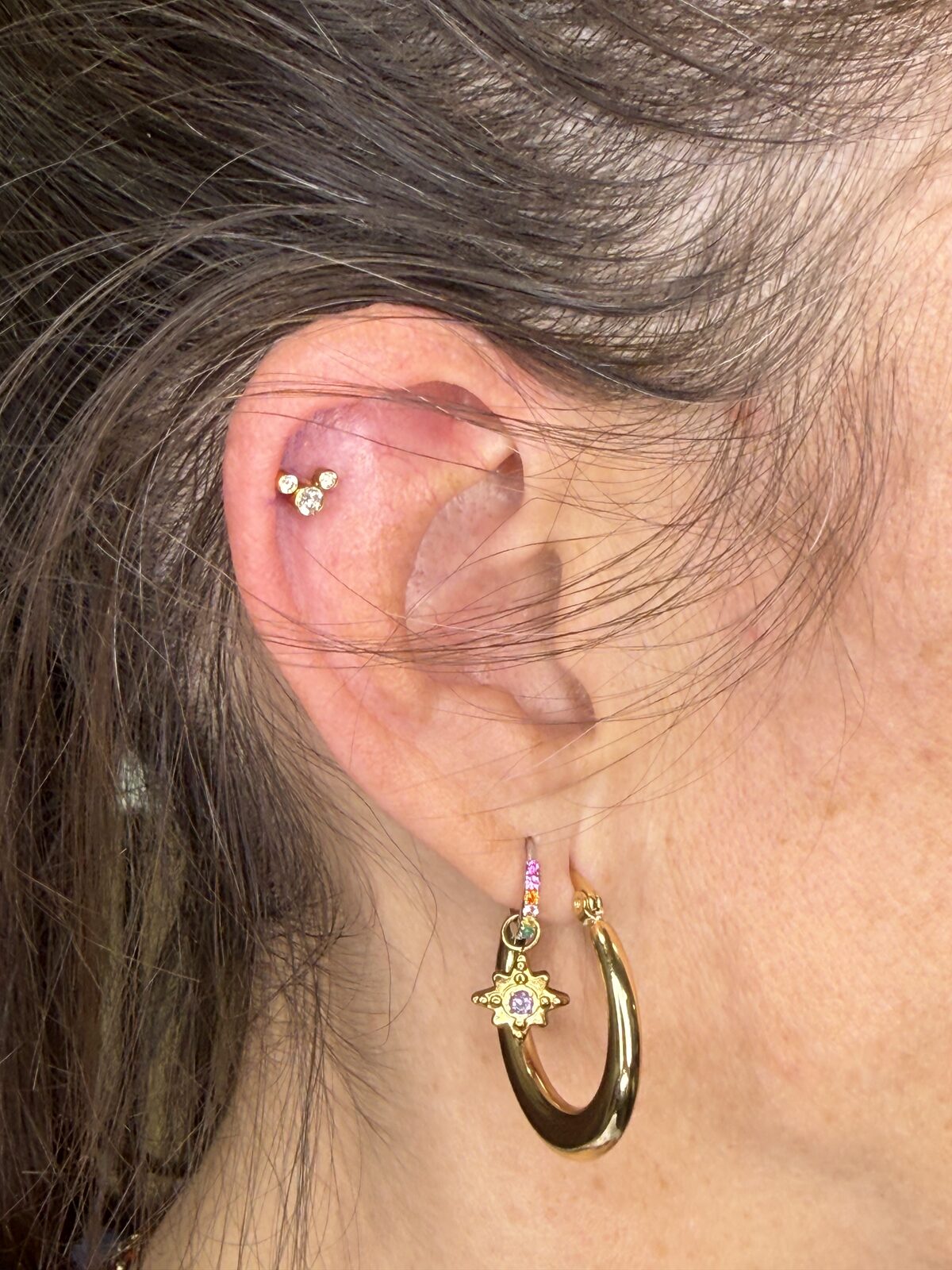 Piercing helix con flor de circonitas y aro dorado en el lóbulo