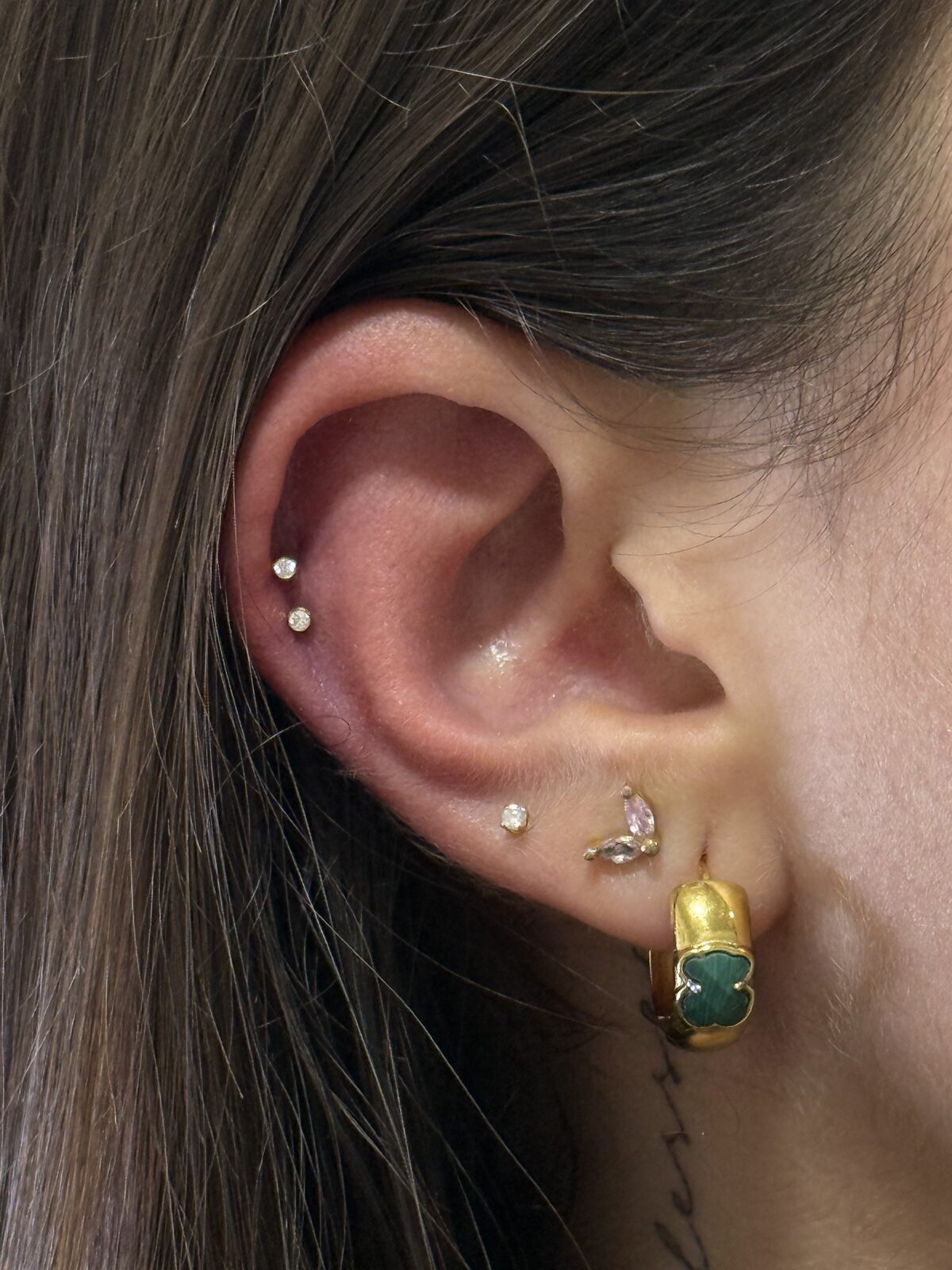 Piercings en helix y lóbulo con joyas doradas