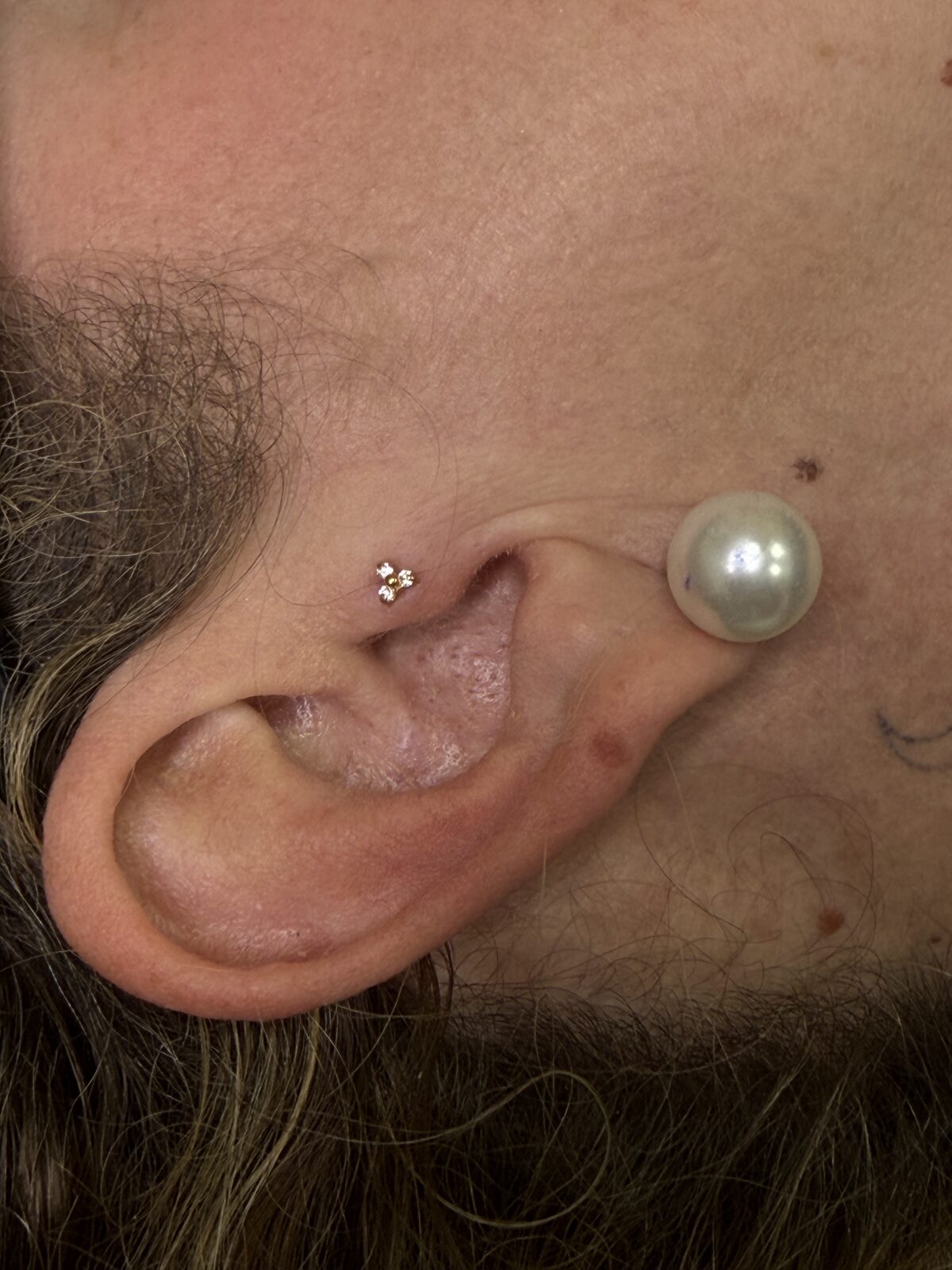 Piercing en la oreja con joya de tres circonitas