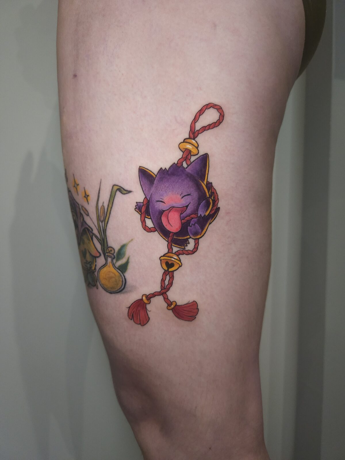 Criatura morada kawaii colgando de un amuleto japonés en el brazo