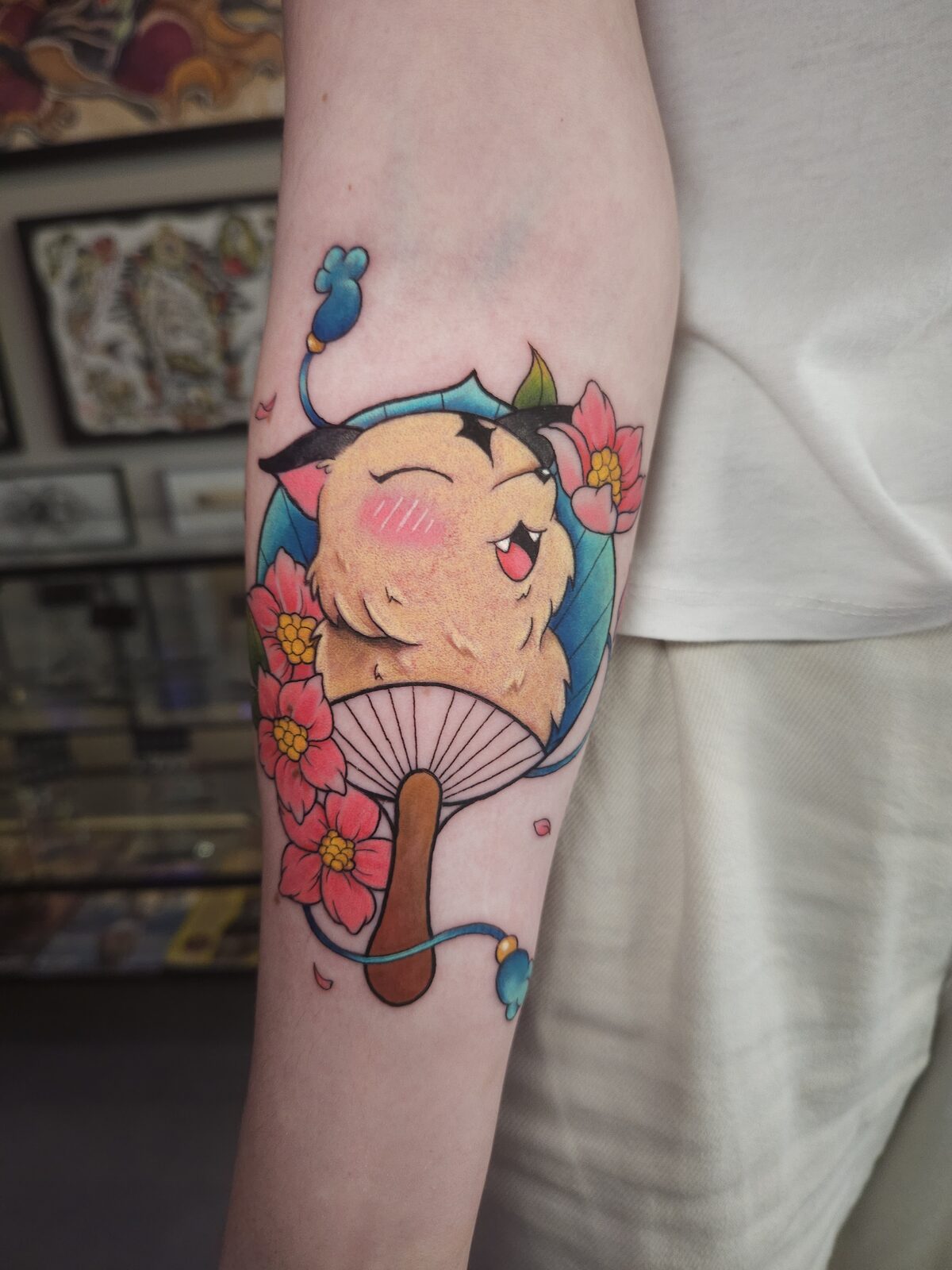 Gato kawaii con abanico japonés y flores de cerezo en el antebrazo