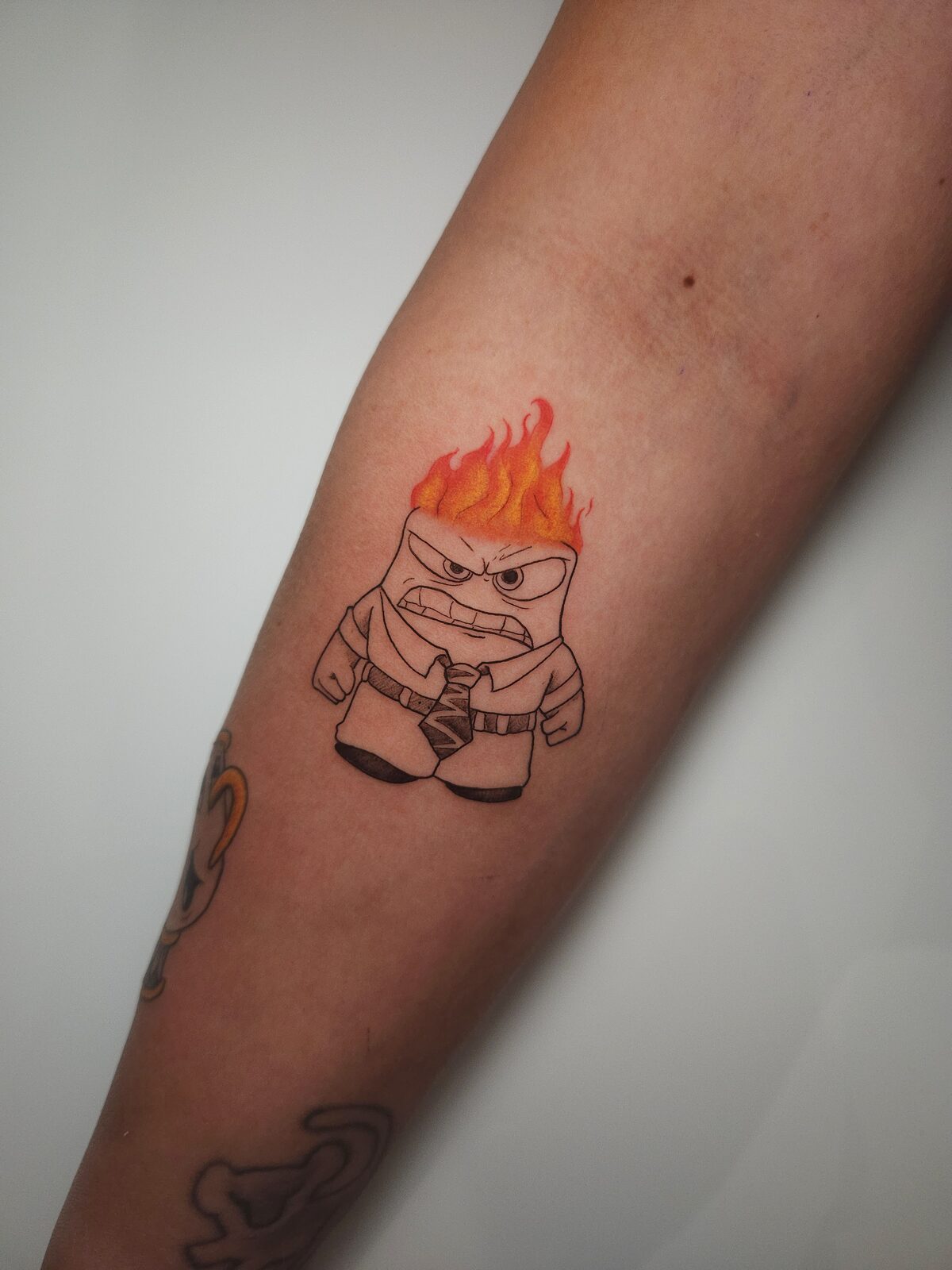 Ira de Del revés con llamas a color en el antebrazo