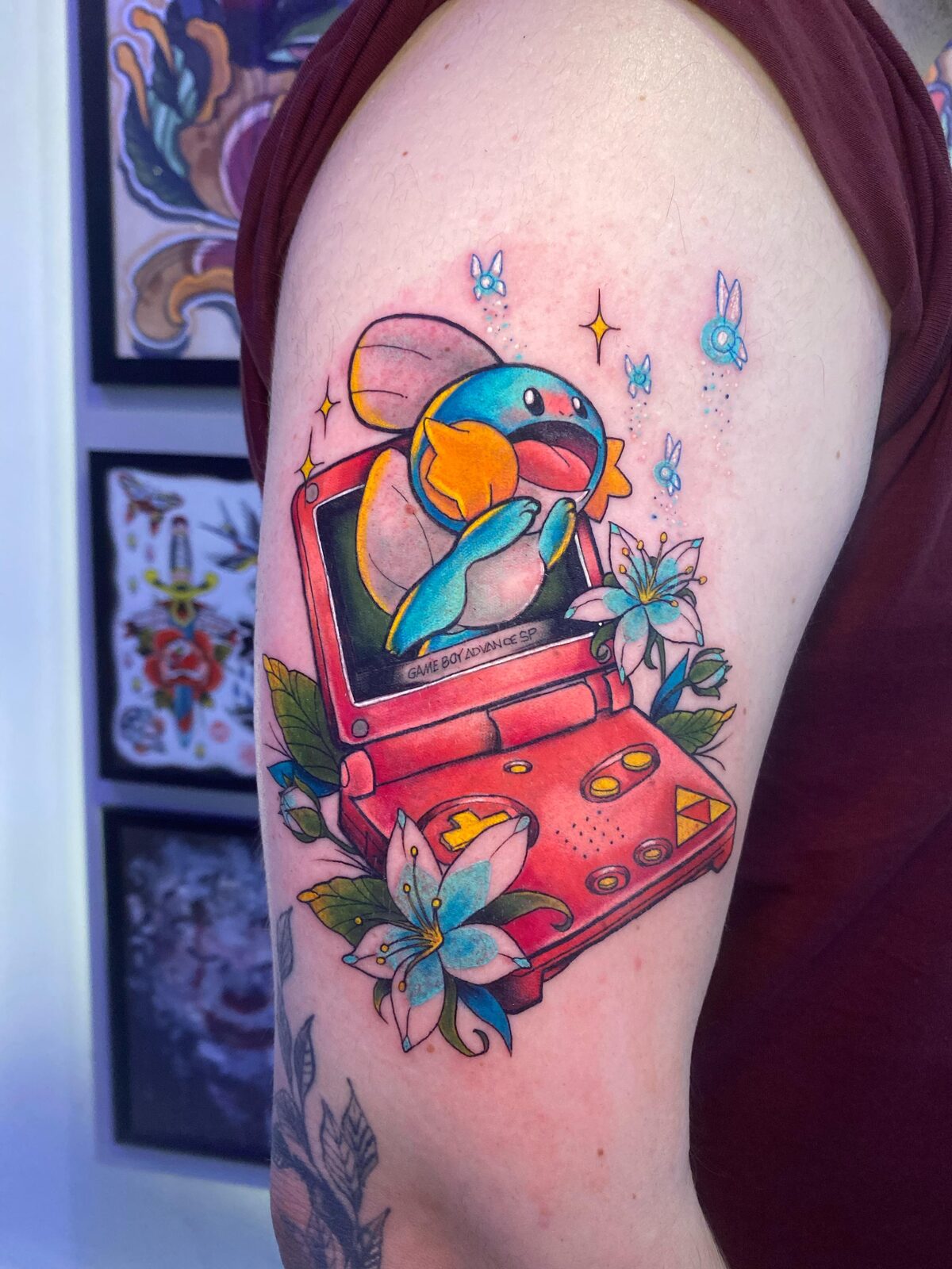 Mudkip de Pokémon saliendo de una Game Boy Advance SP en el brazo