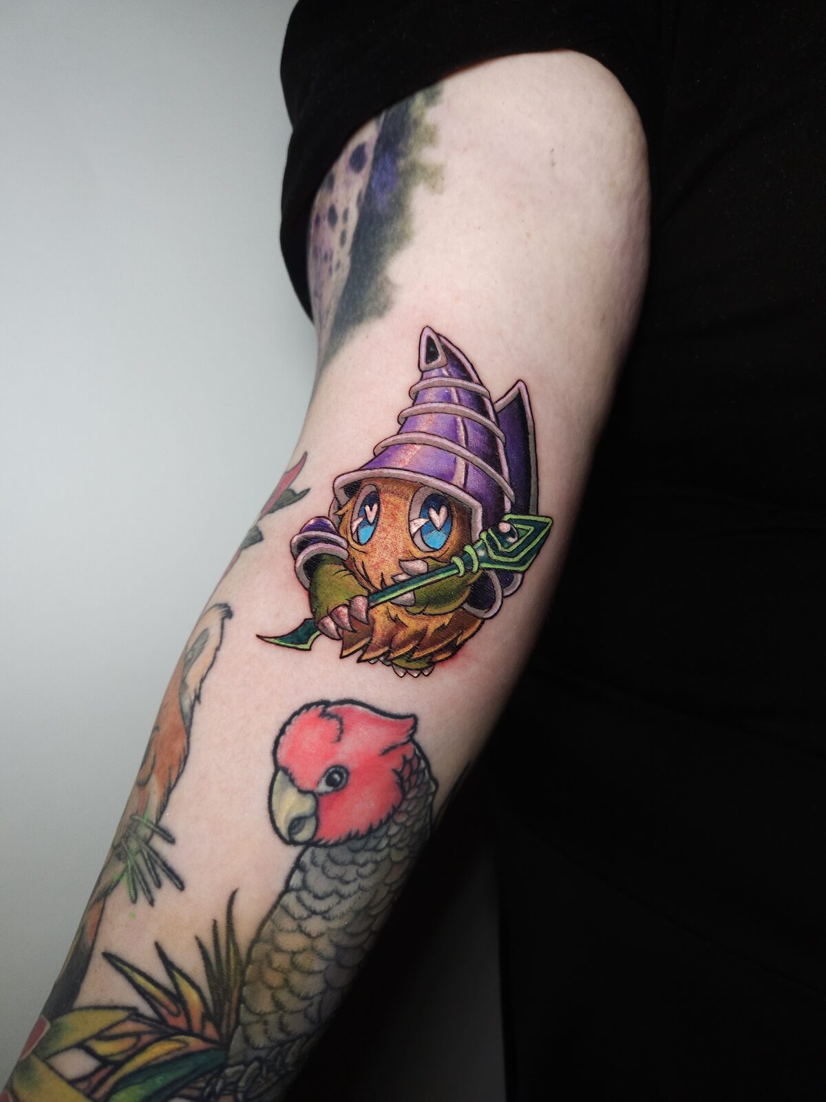 Personaje kawaii con caparazón de caracola y cacatúa a color en el brazo