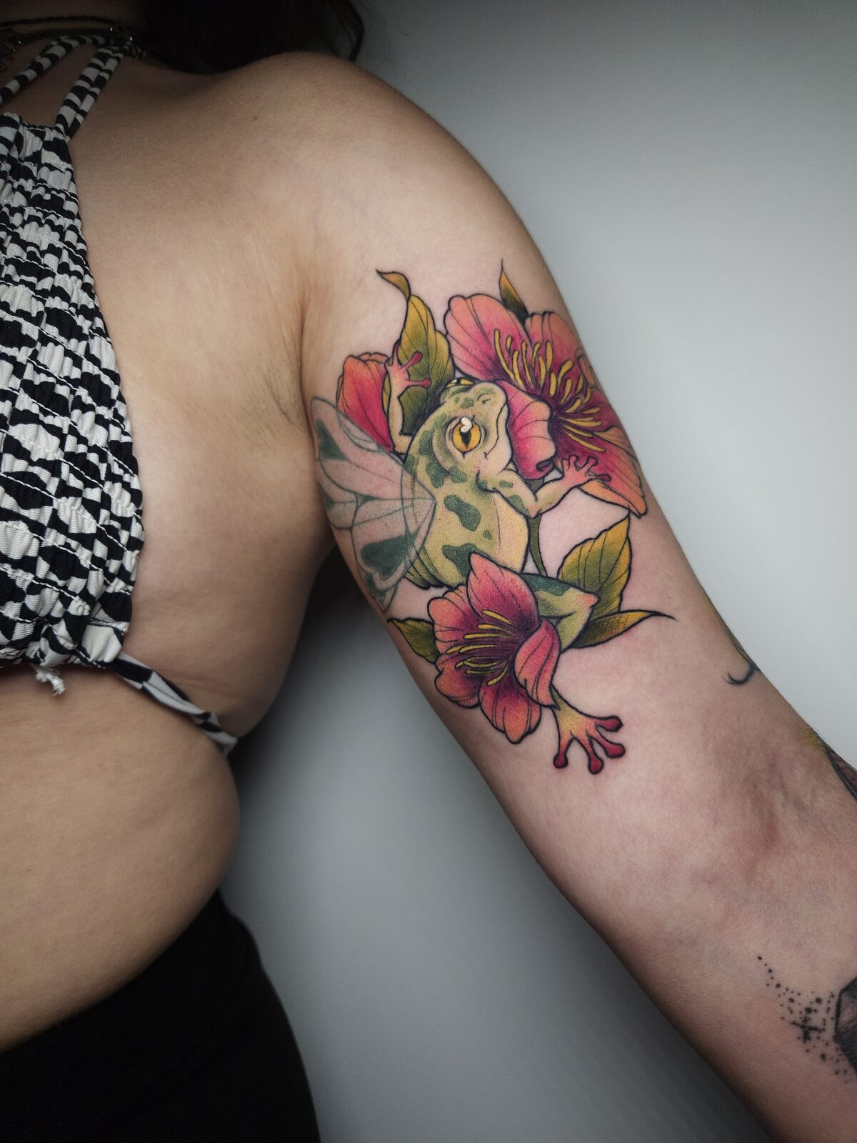 Rana con alas de hada y flores rosas a color en el brazo
