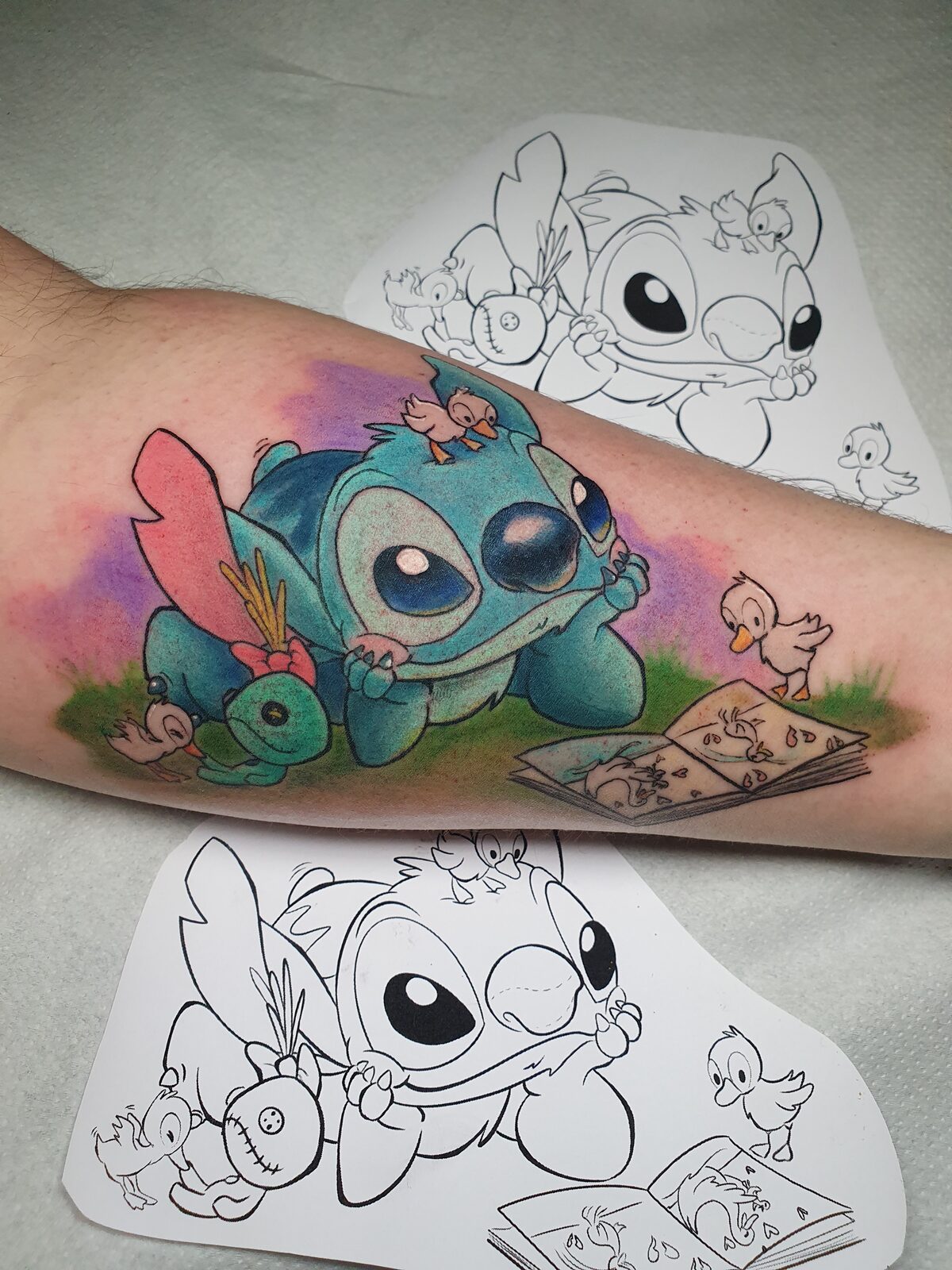 Stitch de Lilo y Stitch leyendo con patitos en el antebrazo