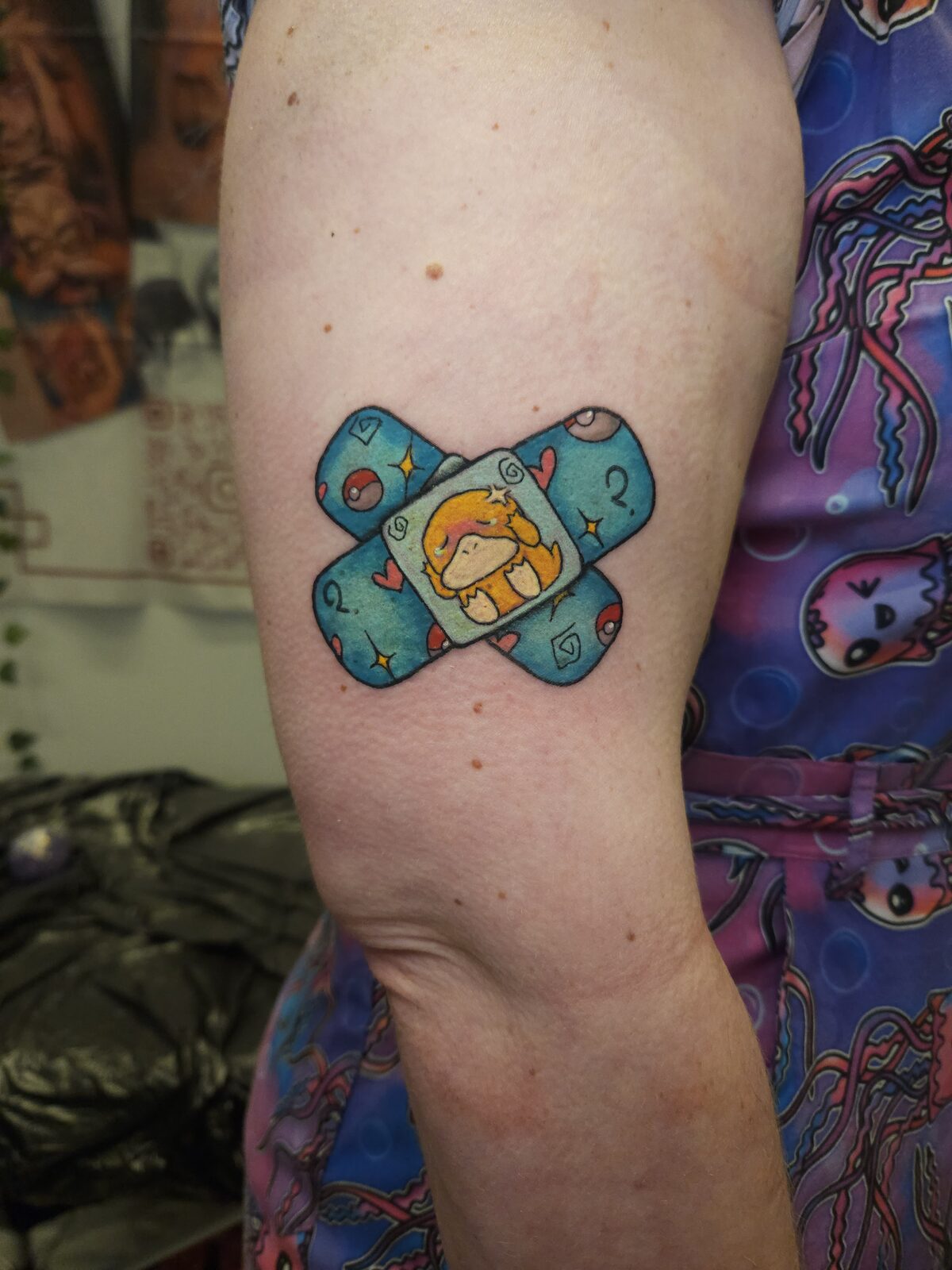 Tirita con Psyduck de Pokémon en el brazo