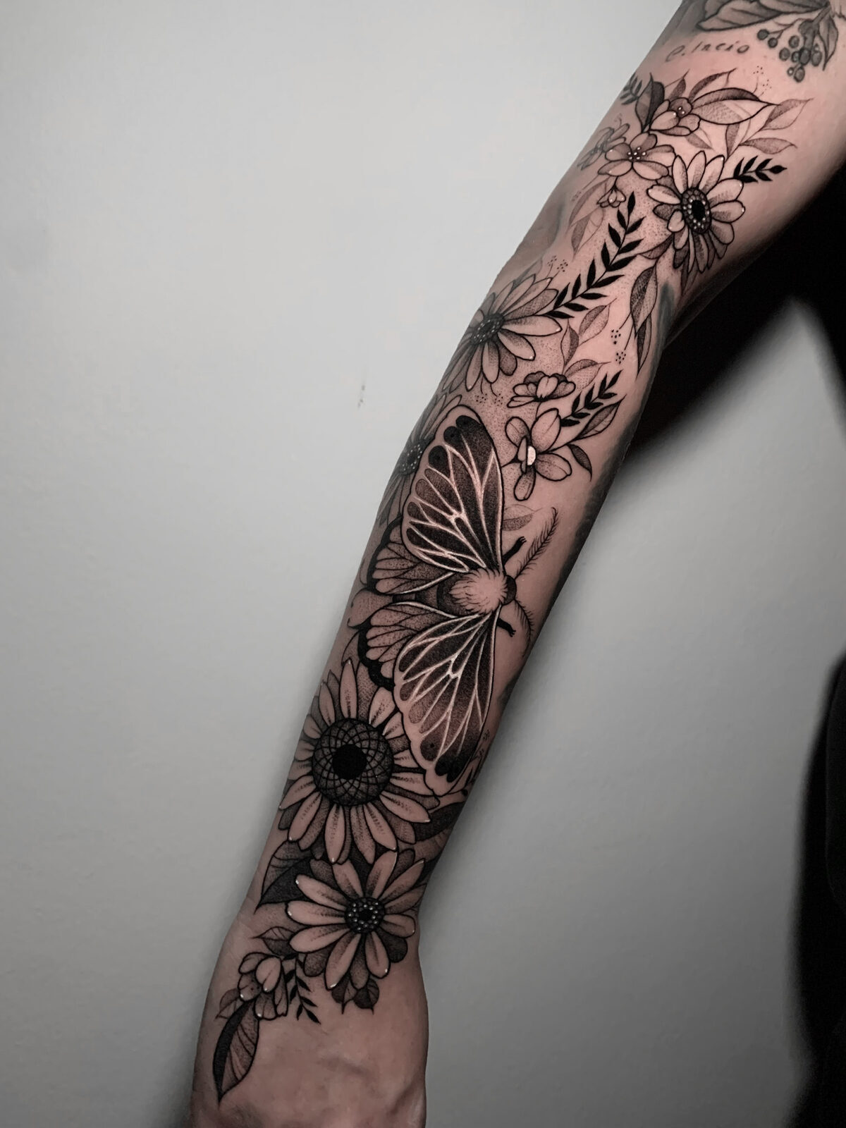 Flores y mariposa en línea negra a lo largo del brazo