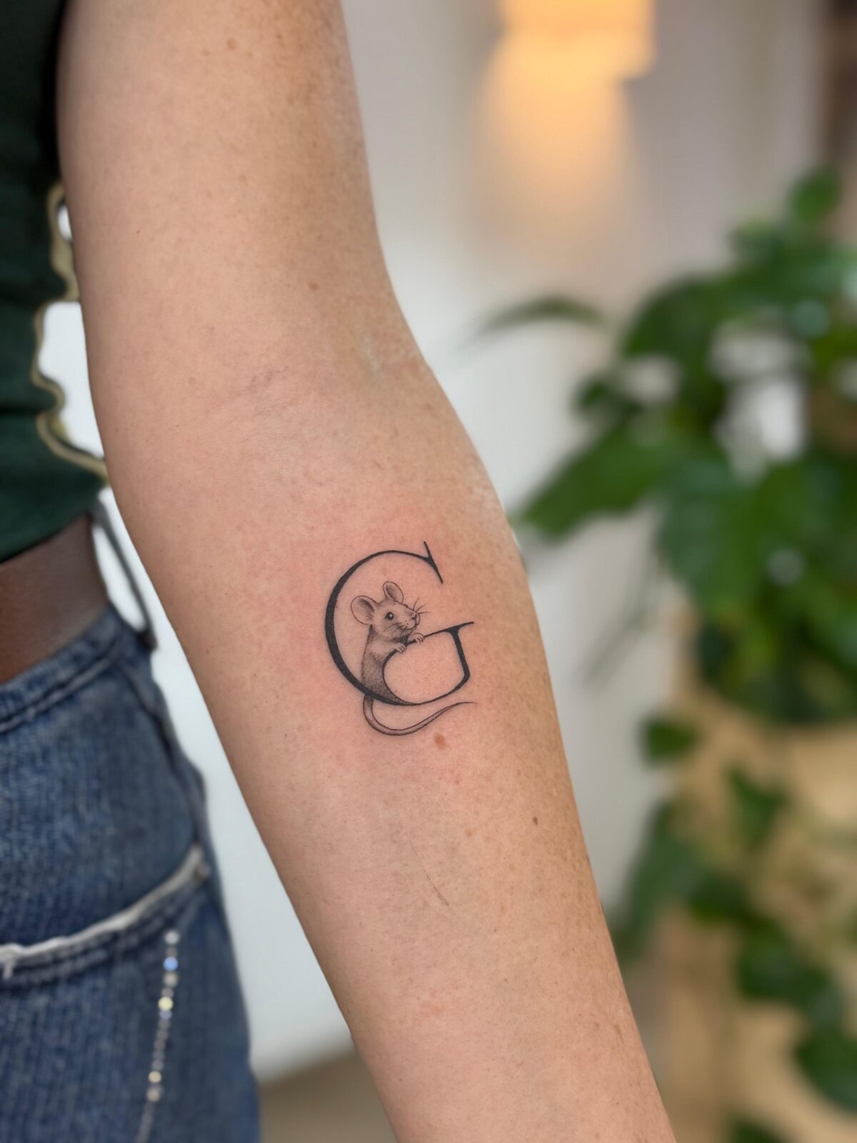 Inicial G con un ratón en línea fina en el antebrazo