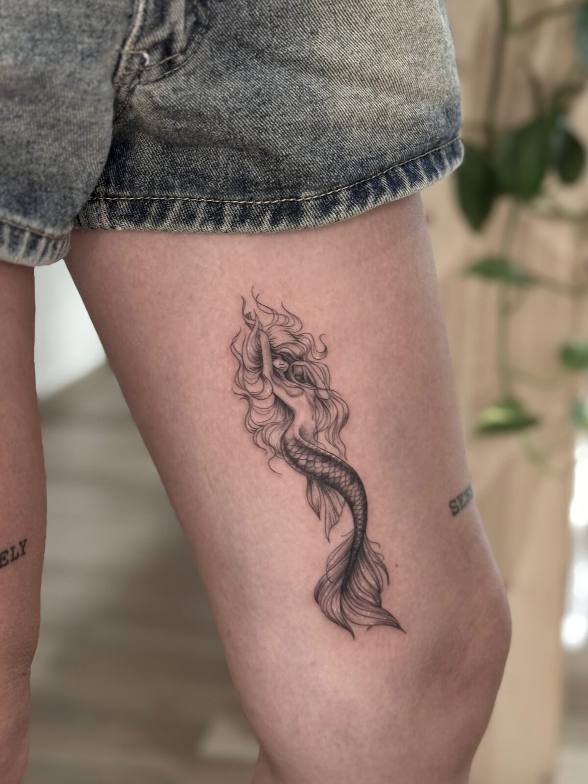Sirena en línea fina con sombreado suave en el muslo