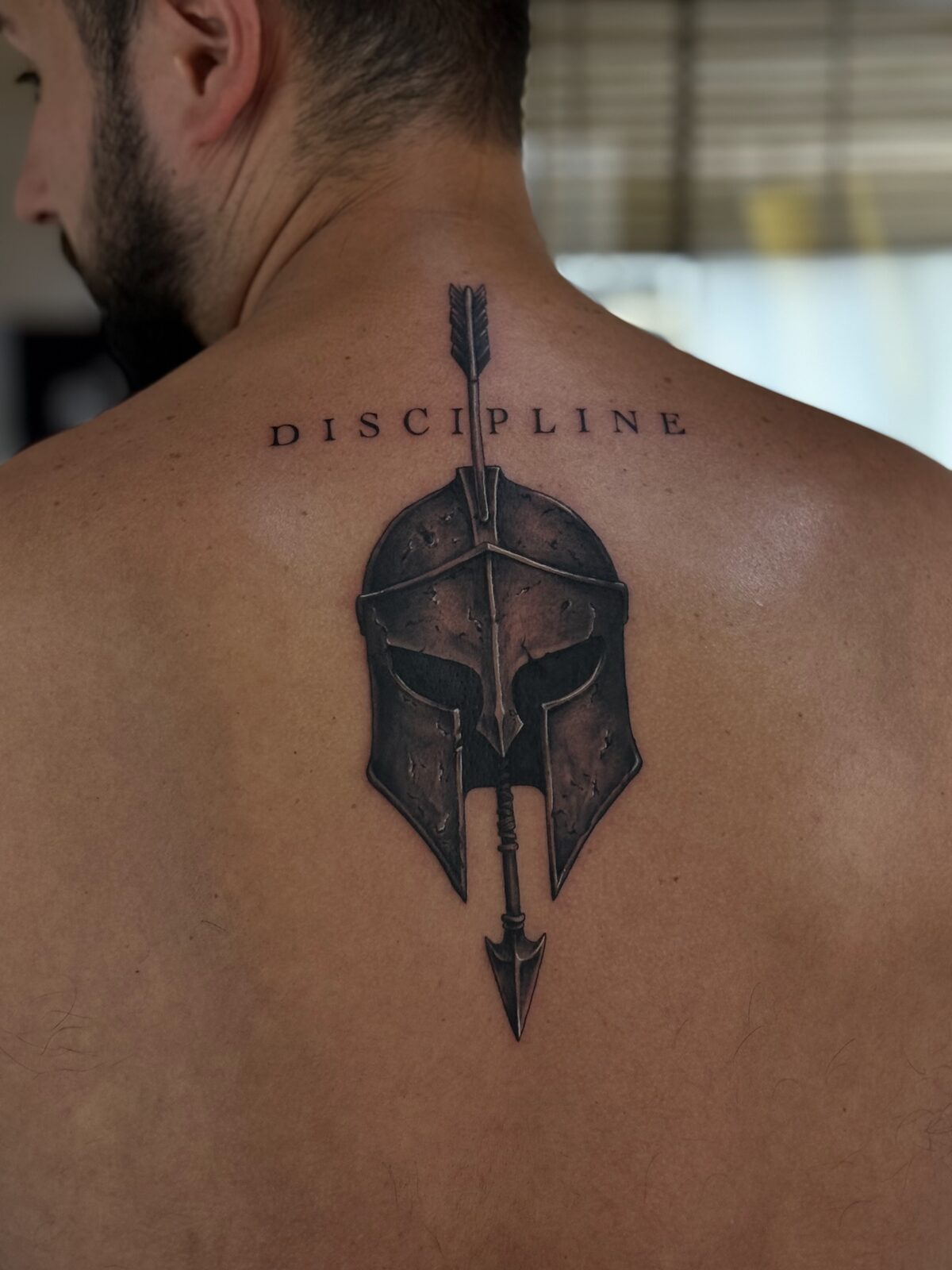 Casco espartano con lanza y la palabra Discipline en la espalda