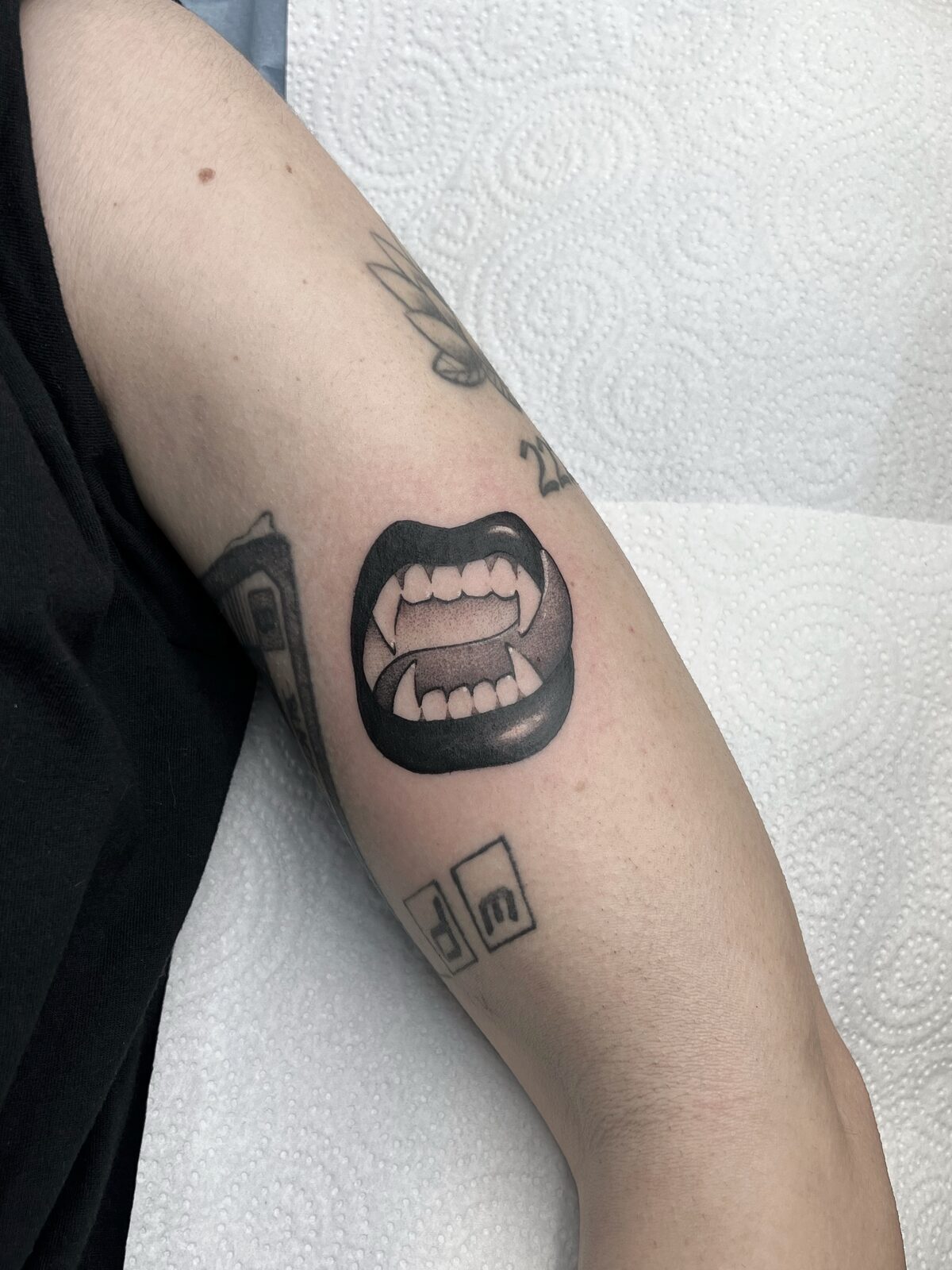 Tatuaje pequeño de boca con colmillos de vampiro en el brazo