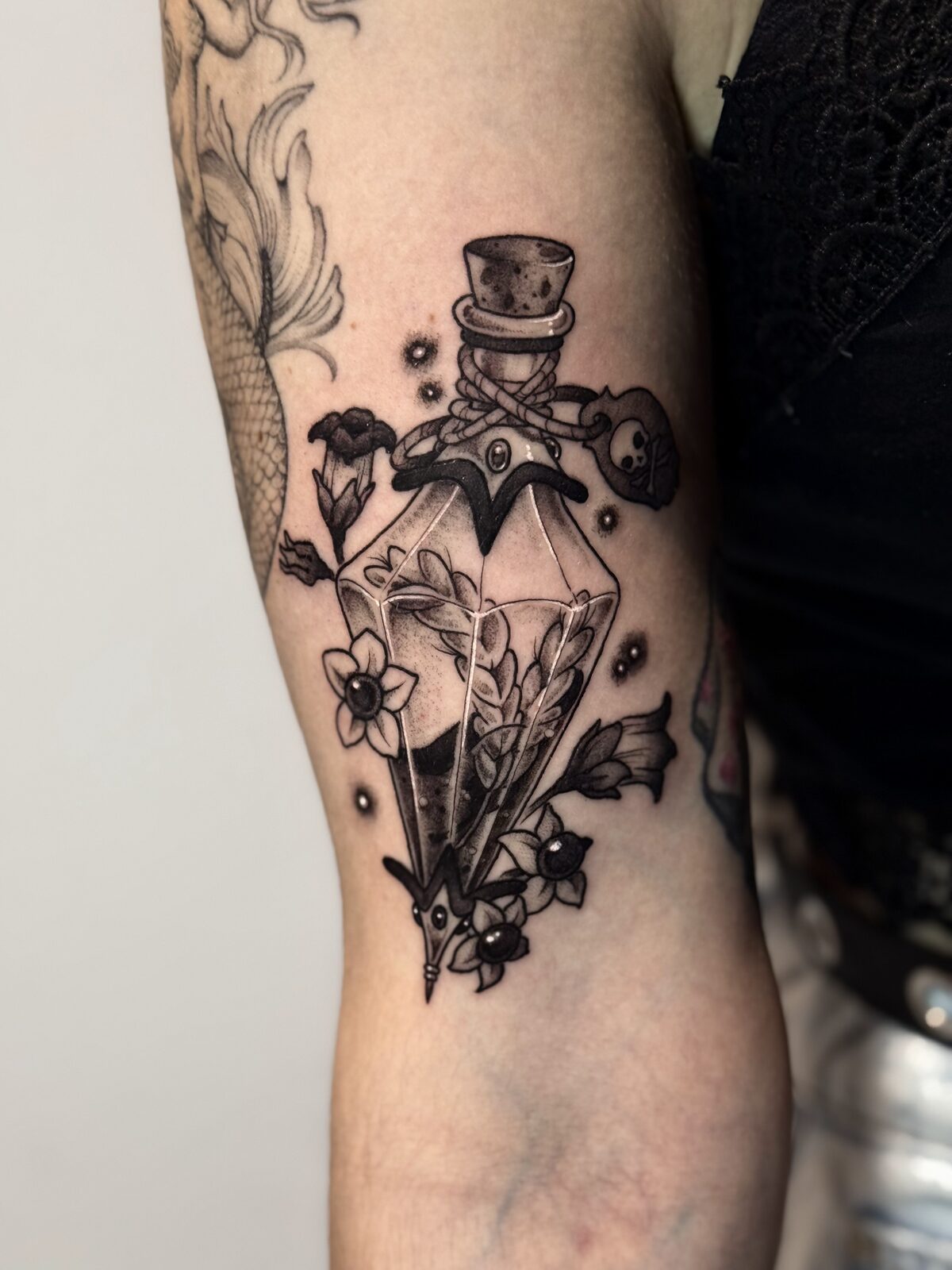 Frasco de perfume con chistera y flores en el brazo