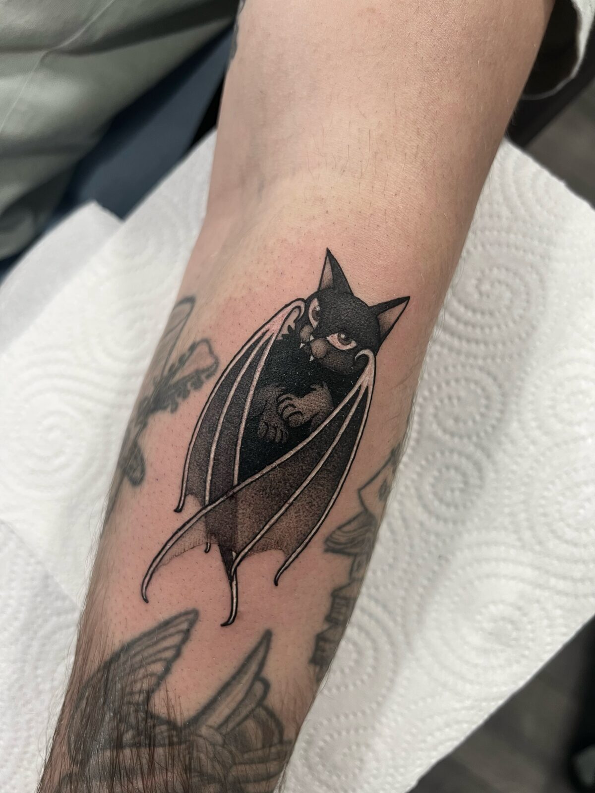 Gato negro con alas de murciélago en el antebrazo