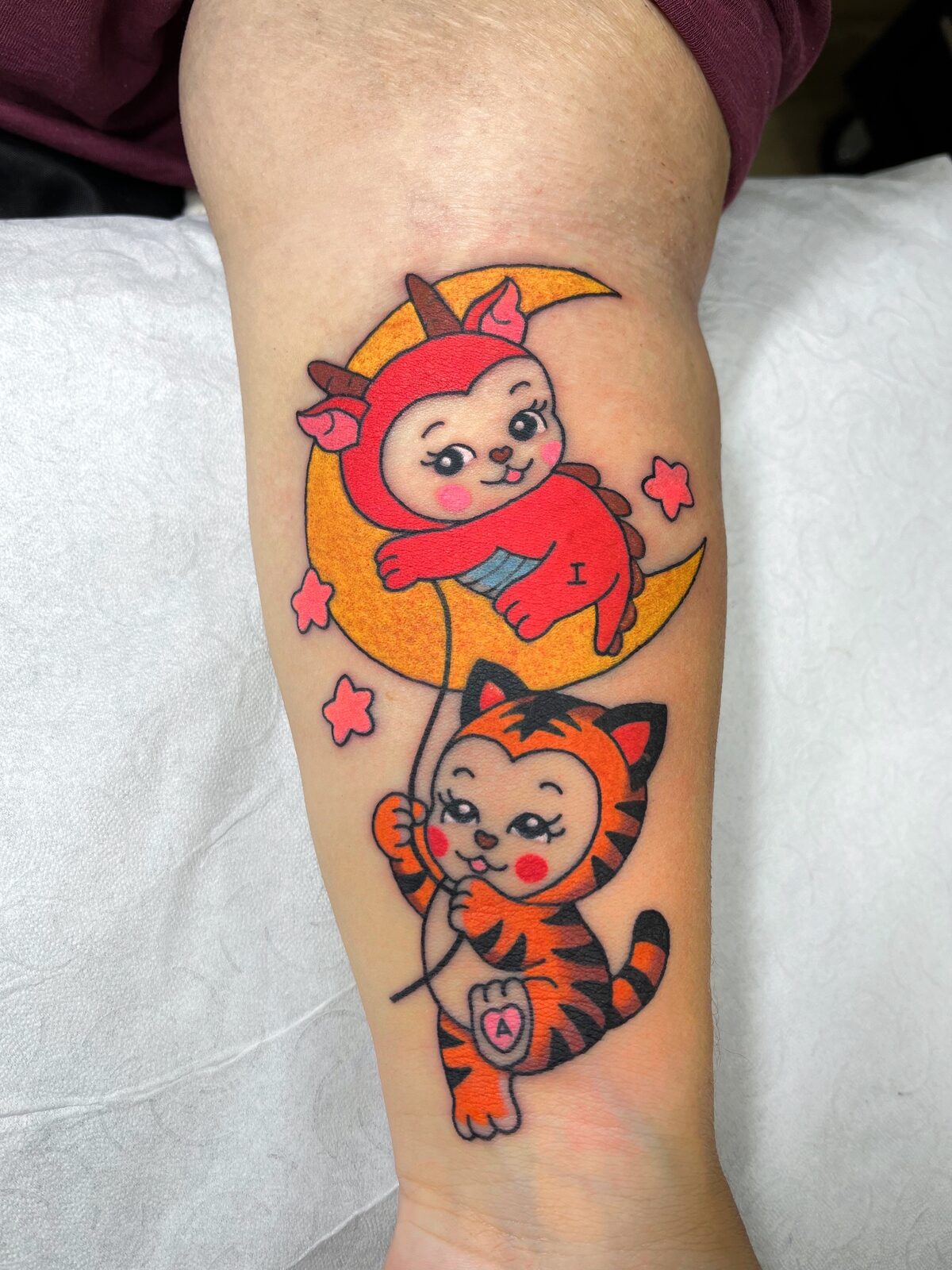Gatito disfrazado sobre la luna y gatito tigre en el antebrazo