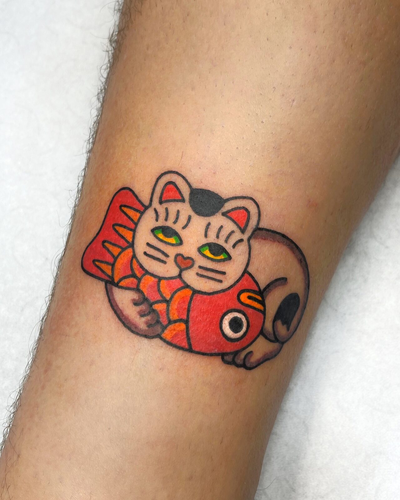 Maneki-neko con pez rojo en el brazo