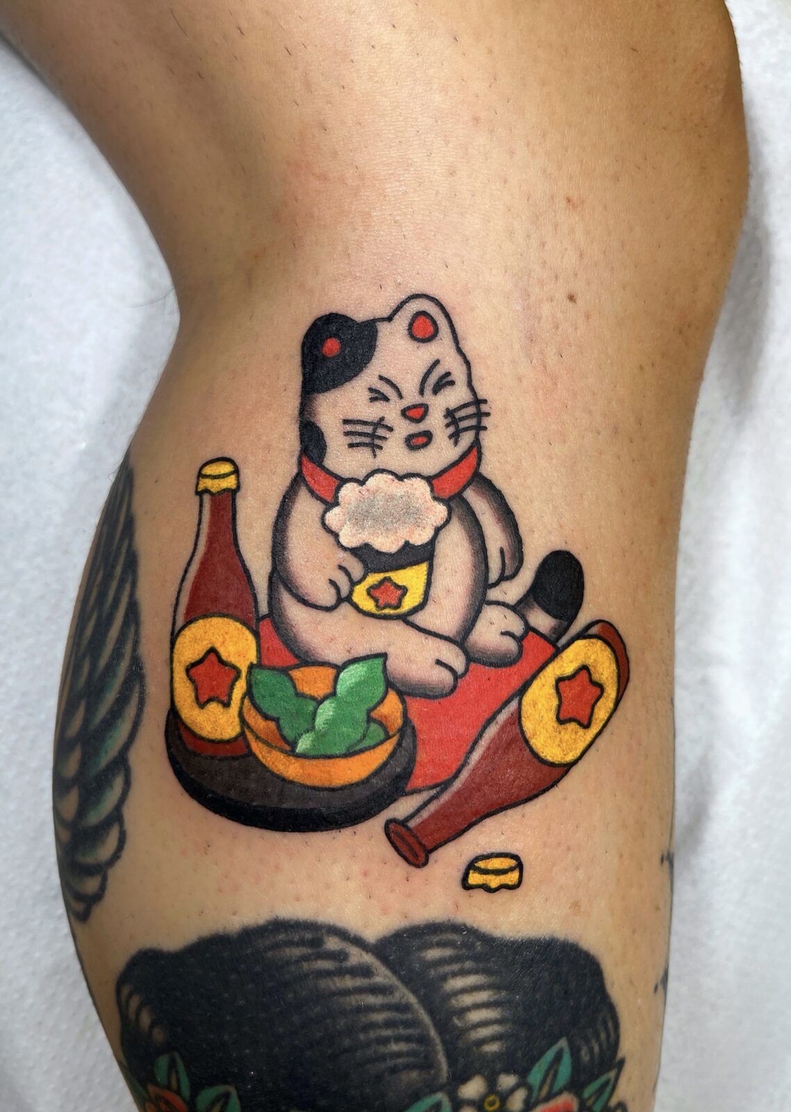 Maneki-neko con botellas de sake y monedas en la pierna