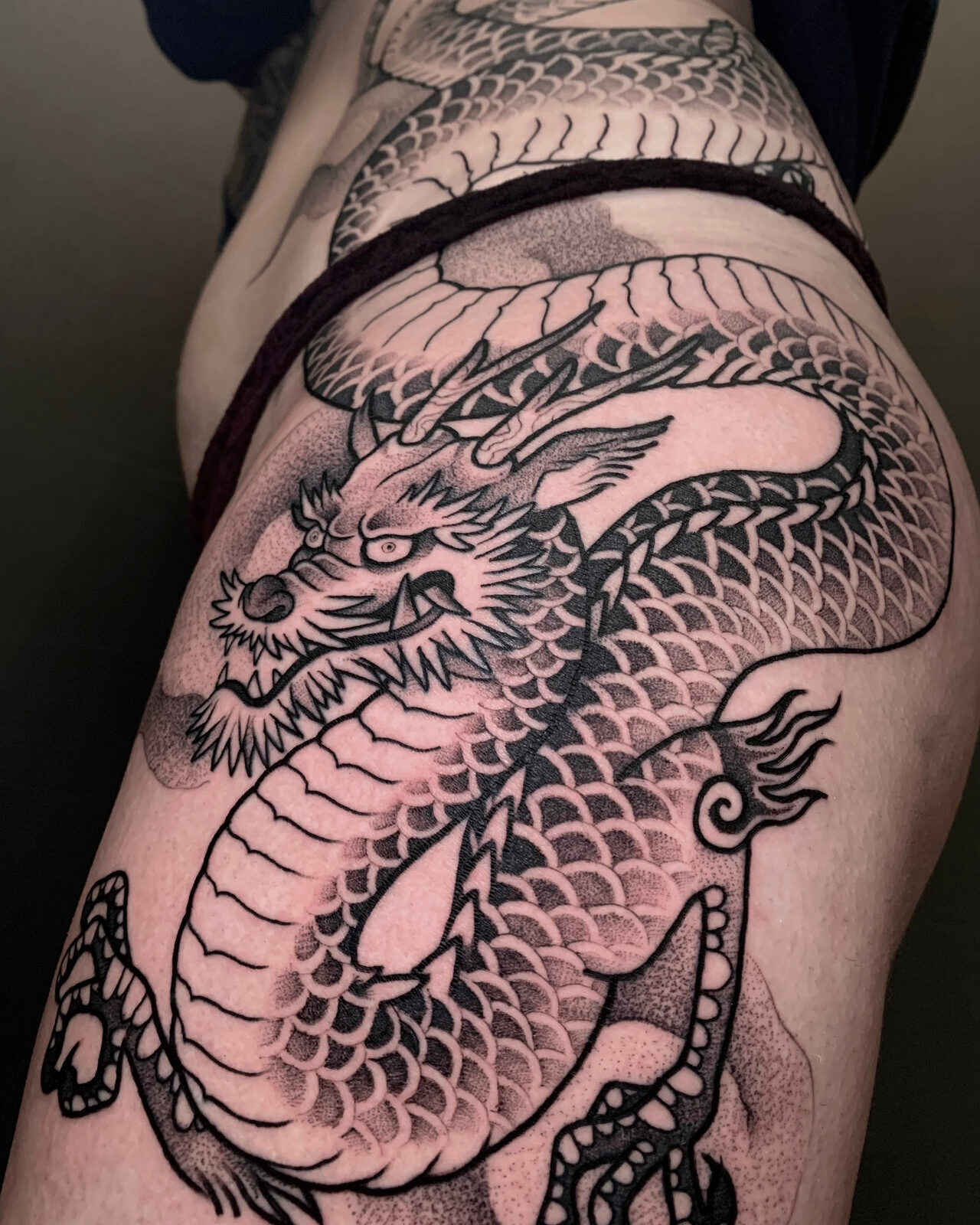 Dragón ilustrativo en negro y grises en la cadera y el muslo