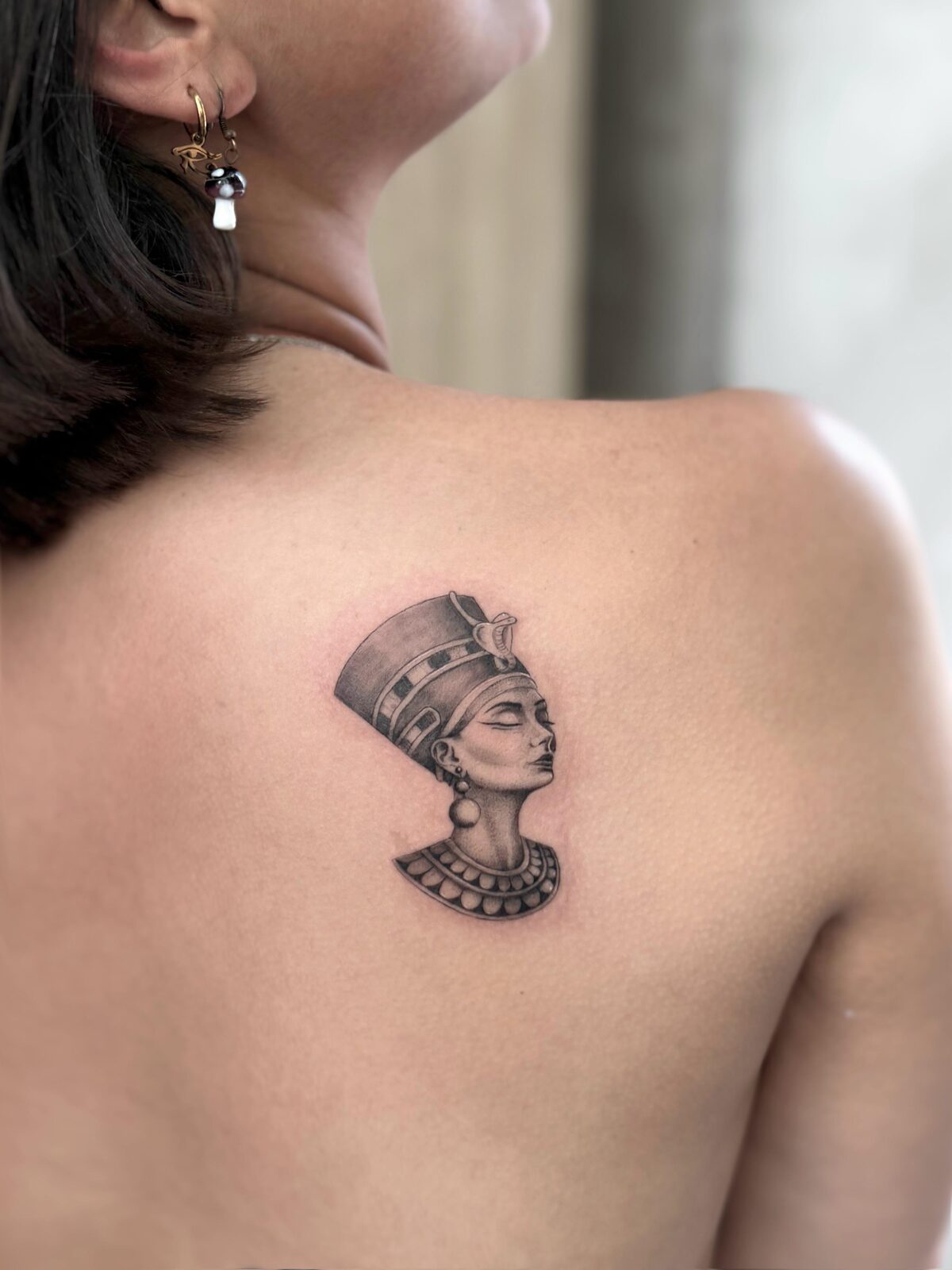 Busto de Nefertiti en microrealismo en el omóplato