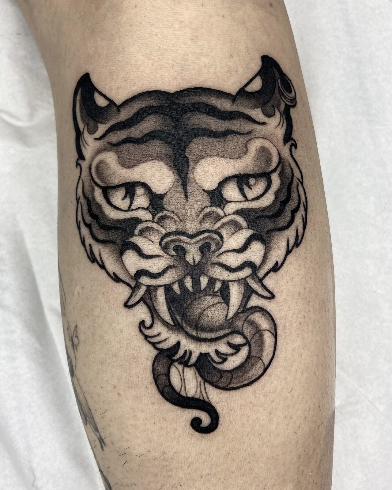 Cabeza de tigre en negro y grises en la pierna