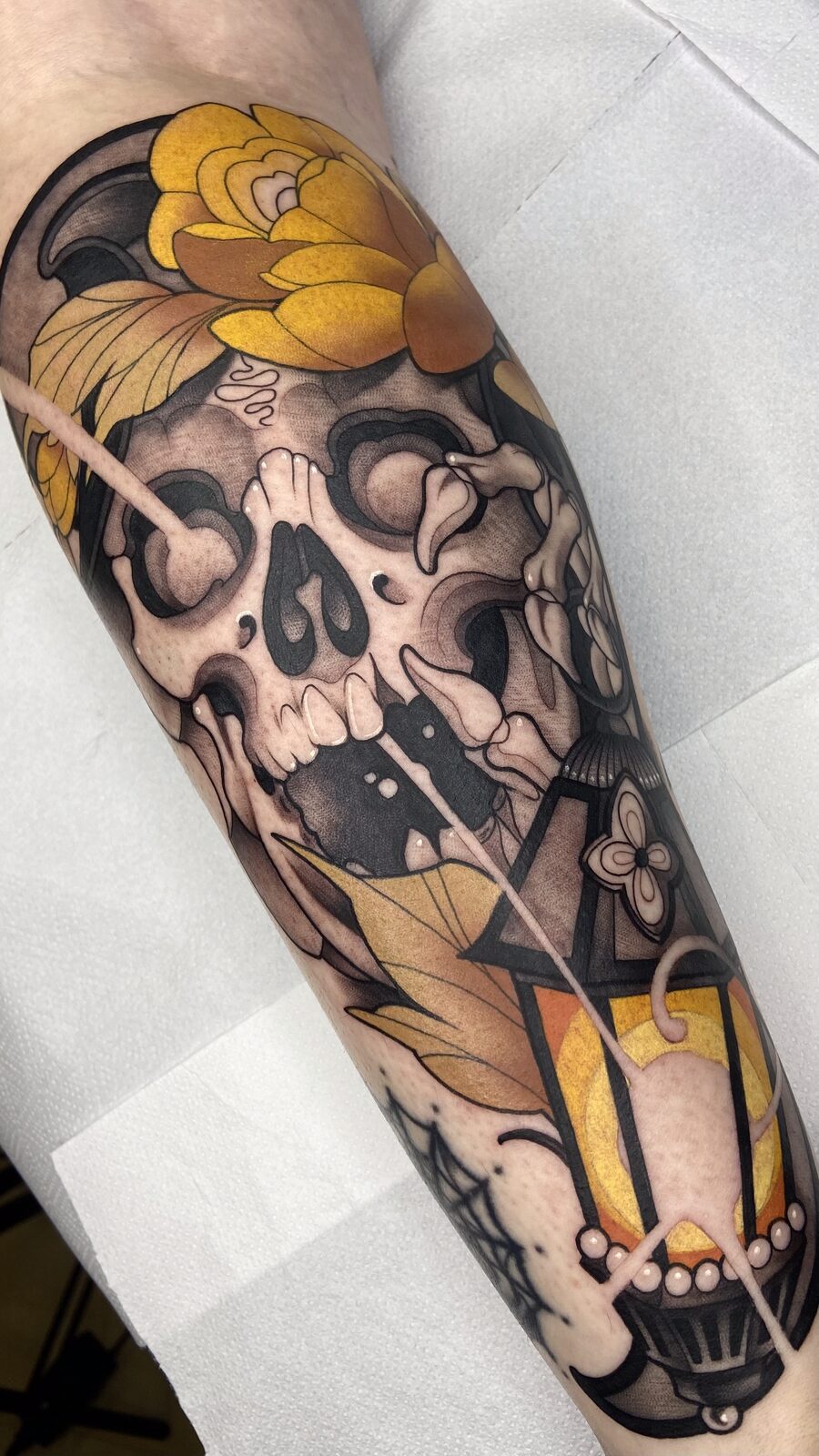 Calavera con crisantemo y farol en el antebrazo