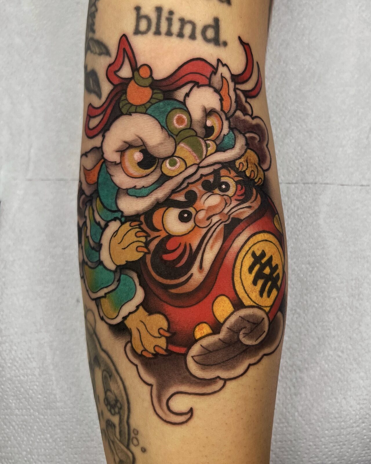 Daruma con máscara de shishi a color en el brazo
