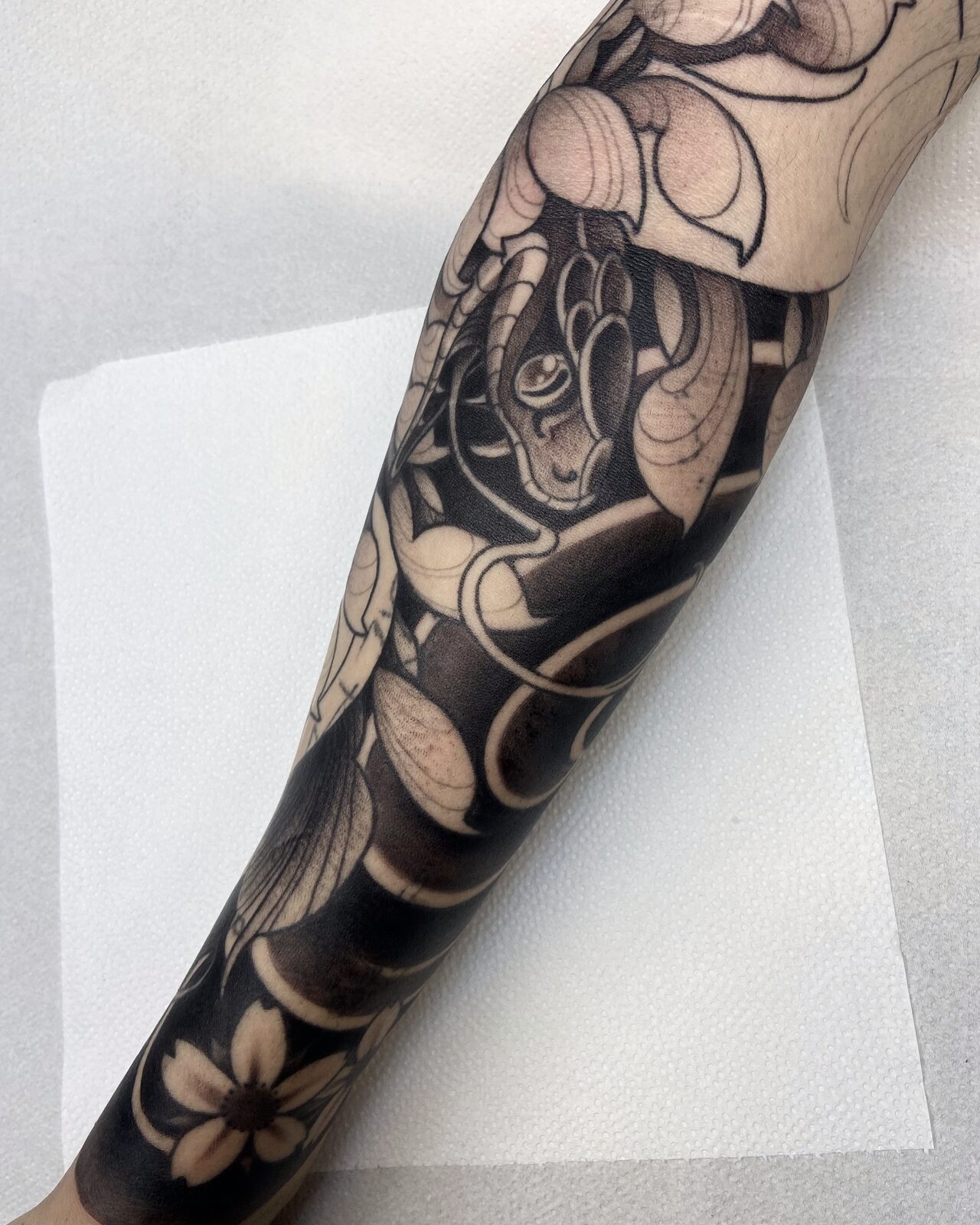 Manga en negro sólido con flores en el antebrazo