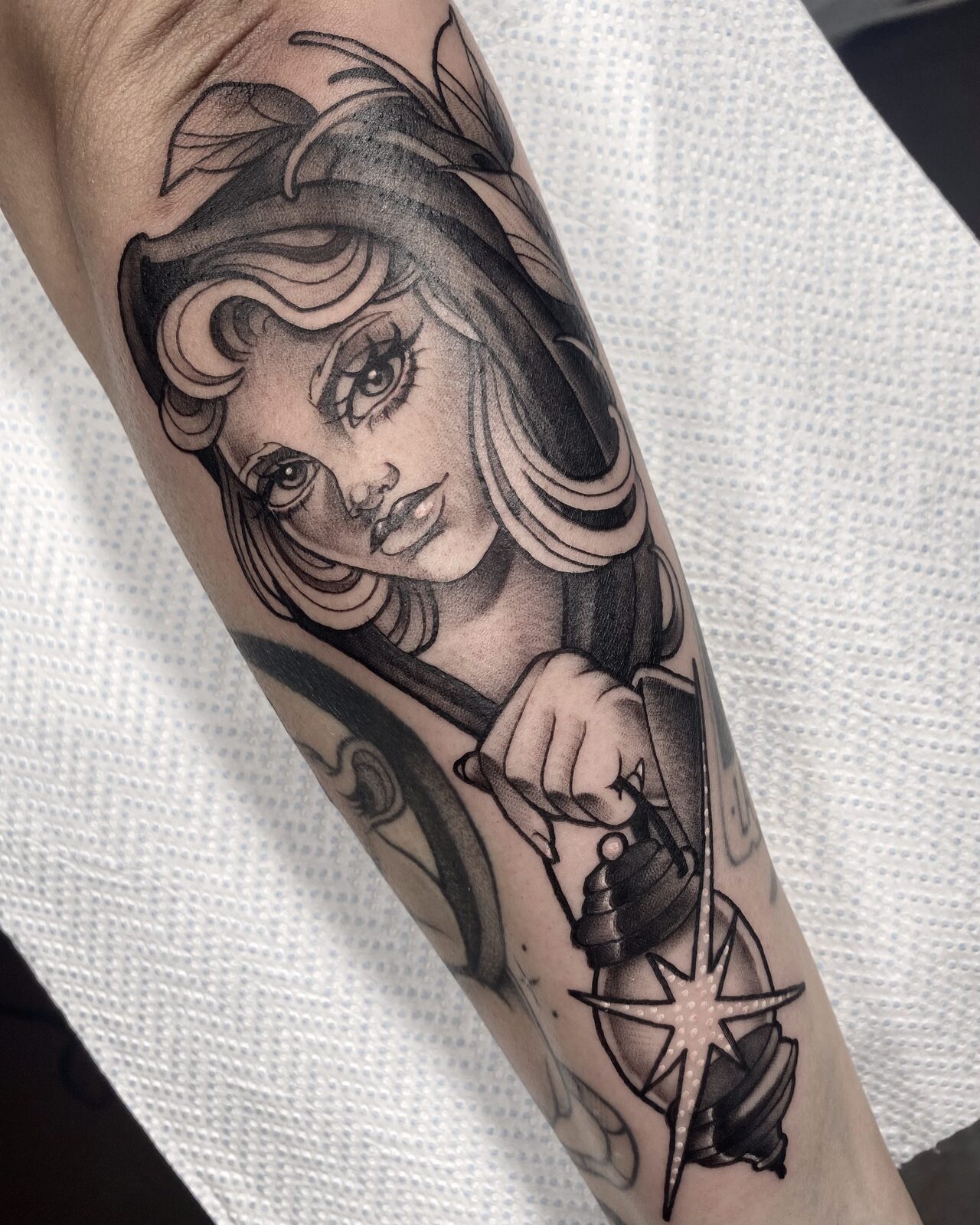 Mujer con farol y estrella en negro y grises en el antebrazo