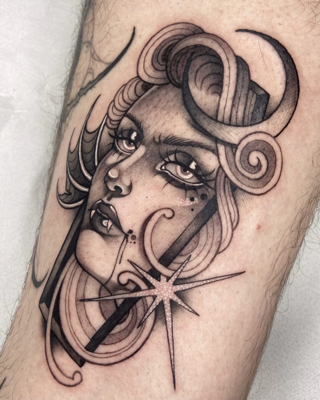 Mujer con luna y estrella en negro y grises en el antebrazo